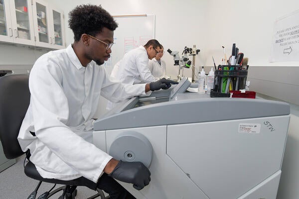 Researcher working on machine, with two other researchers in the background